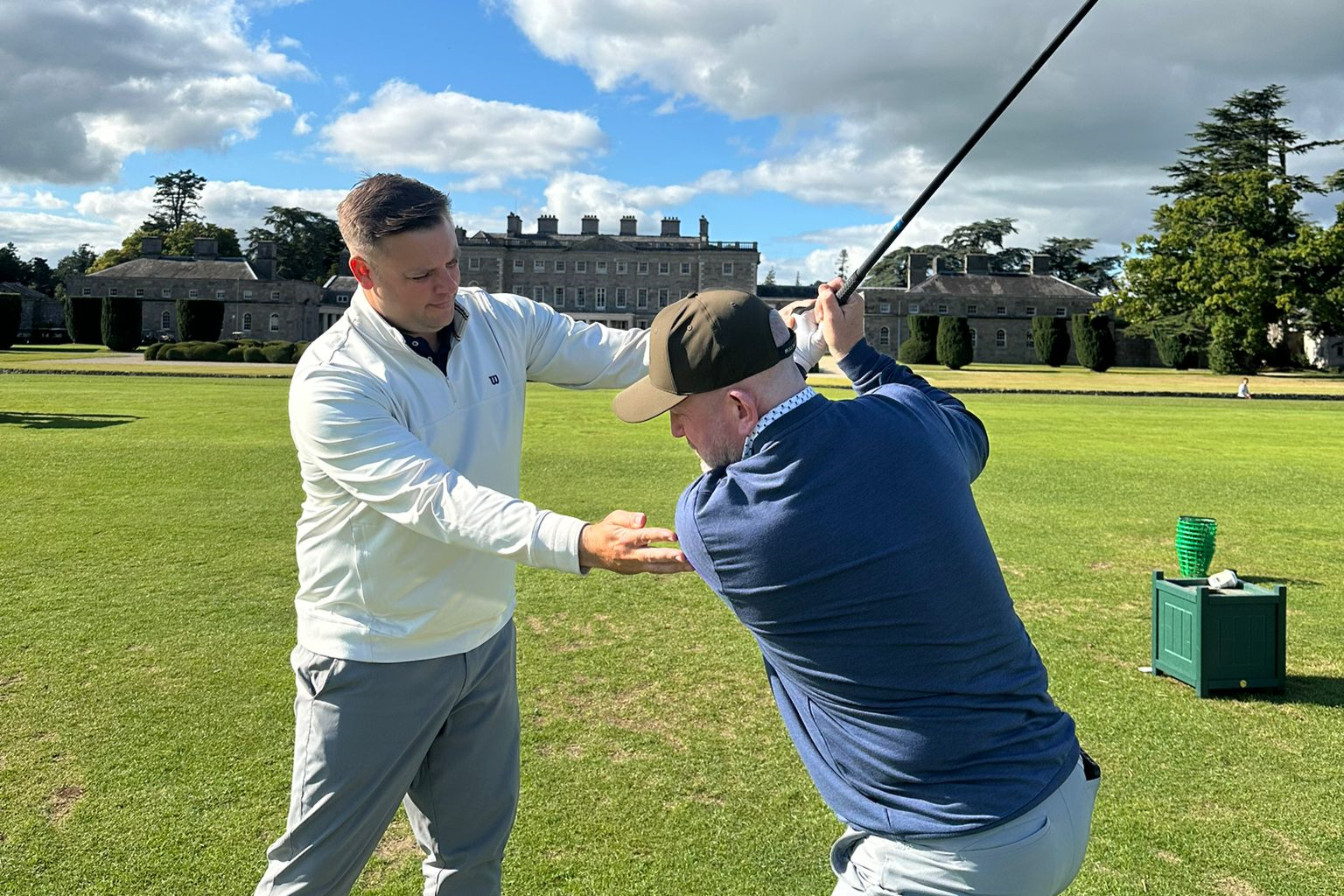 Photo of a golfer getting coaching on a golf course on a cloudy day